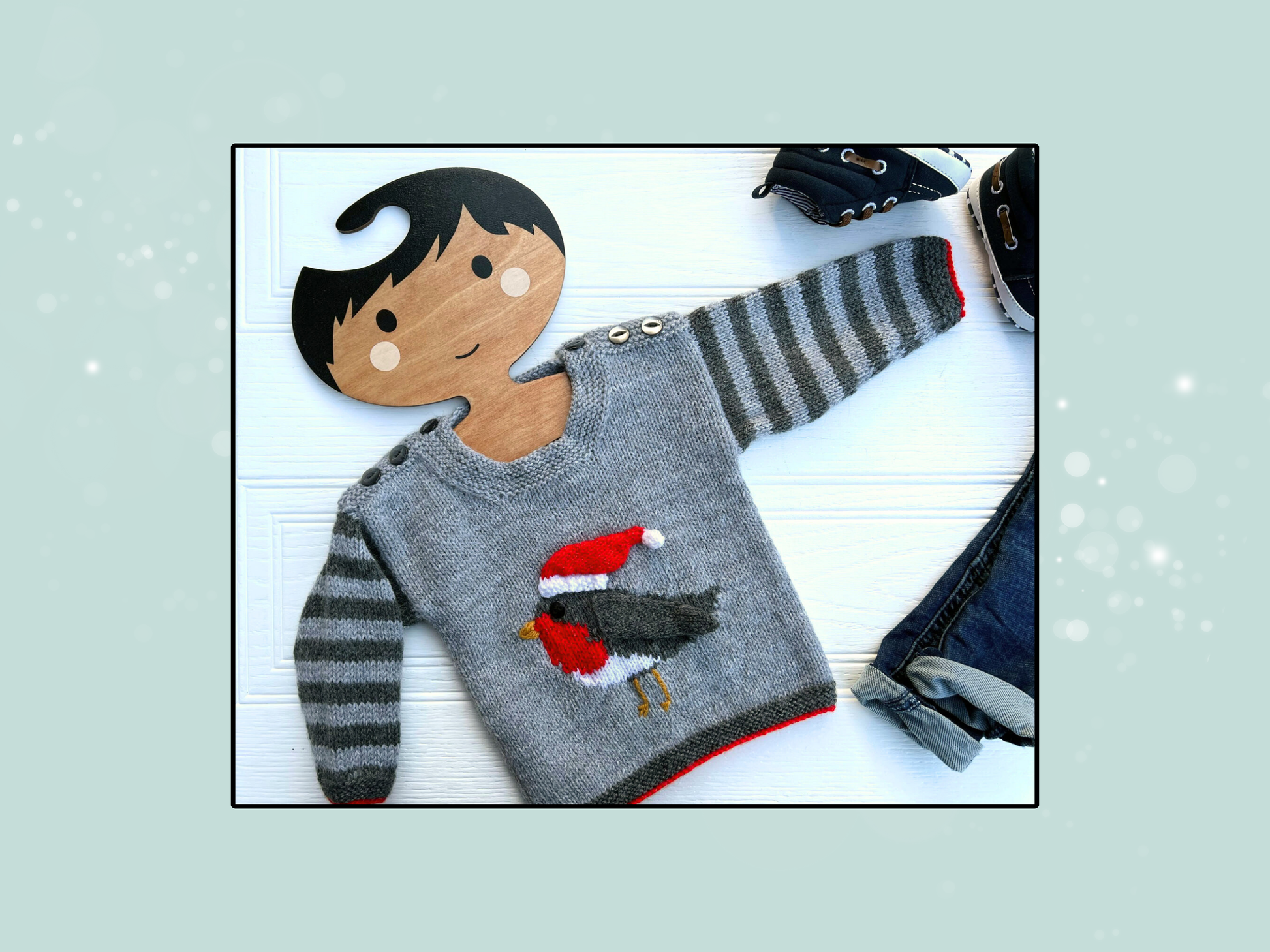 Rocking robin baby sweater knitting pattern, grey striped sleeves, with an intarsia robin on the front, the wing and hat are knitted and sewn on. The Hat can be removed after Christmas. DK yarn, designed by Jane Burns