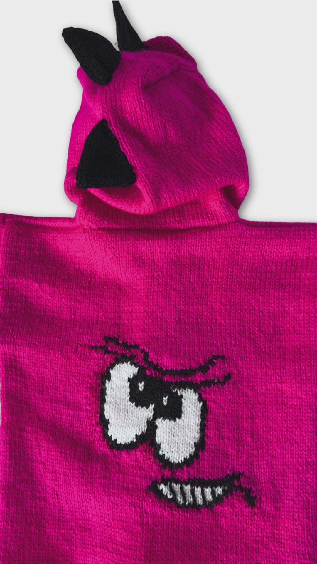 Pink knitted hoodie with cartoon face design on the back and black spikes on the hood, knitting pattern for kids hooded cardigan jane burns