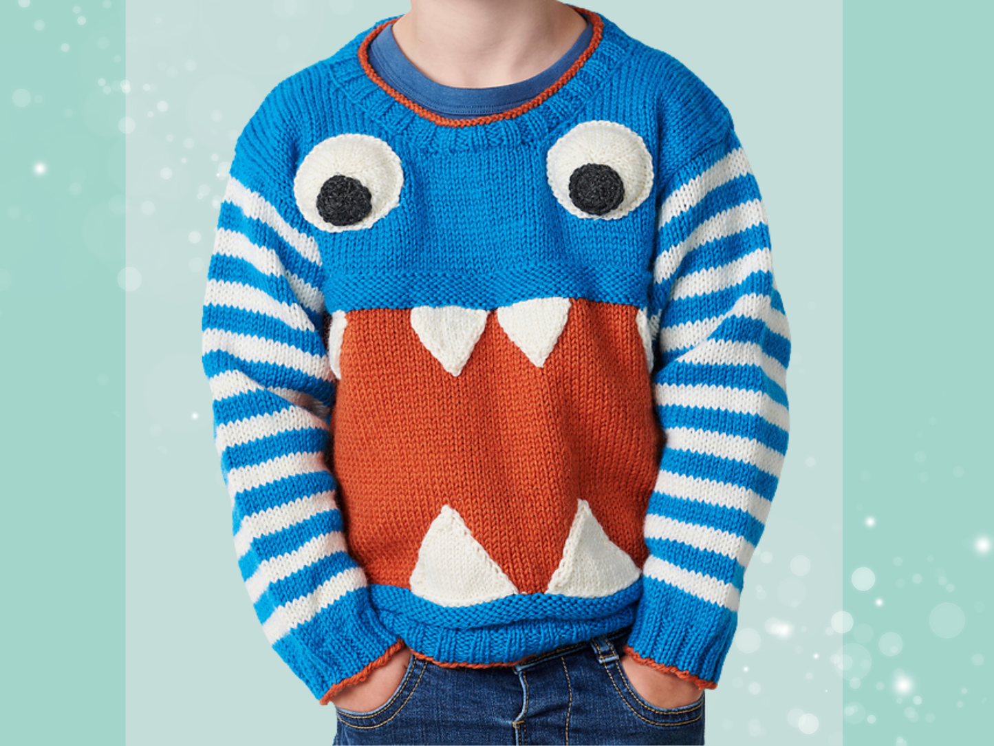 Monstrous kids sweater knitting pattern, a blue sweater with striped sleeves. A large red section across the tummy with knitted teeth and large googly eyes makes this jumper both cute and terrifying, no intarsia. Knitting pattern by Jane Burn