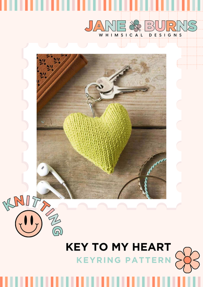Heart-shaped knitted keychain on a wooden surface with 'Jane Burns Whimsical Designs' branding.