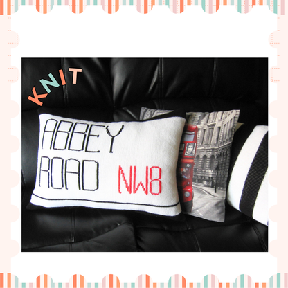Image shows two knitted cushions one showing the abbey road street sign and behind it a second black and white striped cushion looking like the zebra crossing from the beatles music album knitting pattern by jane burns