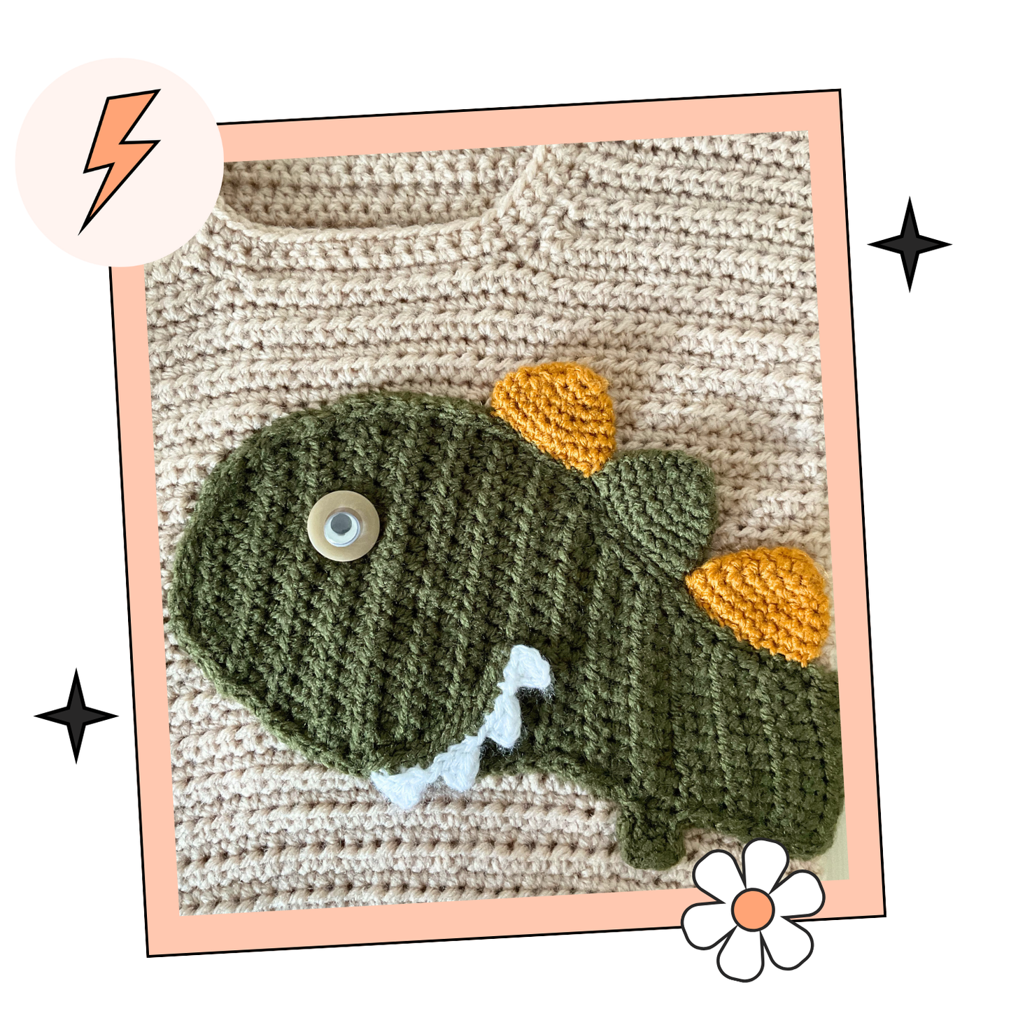 beige crochet sweater with moss green cuff, featuring a moss green dinosaur applique, mustard and moss green spikes run down the spine of the dinosaur. the dinosaur has white teeth and googly eye. the sleeves of the jumper has crochet spots sewn to them. dinotastic crochet sweater pattern for babies and toddlers by jane burns