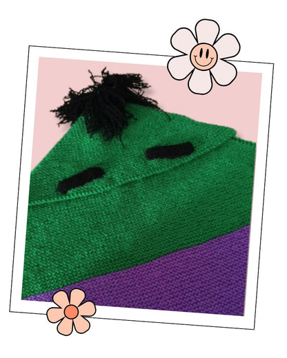 Close-up of green garter stitch Frankenstein monster baby blanket with knitted black eyebrows, Jane Burns knitting pattern