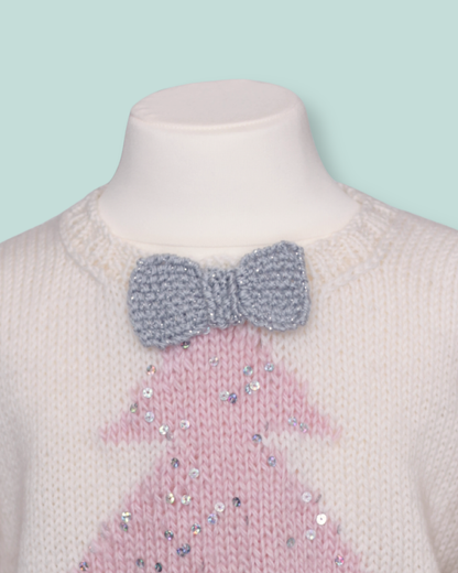 A close-up of a knit sweater displayed on a mannequin neck. The sweater is cream-colored with a pink sequined Christmas tree design and a gray knitted bow at the collar.  sparkle christmas tree jumper for girls knitting pattern by jane burns