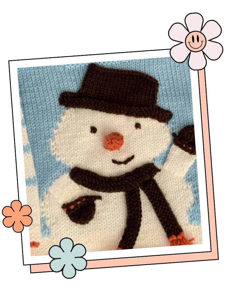 Close-up of knitted snowman motif with top hat, scarf and carrot nose, intarsia baby jumper knitting pattern