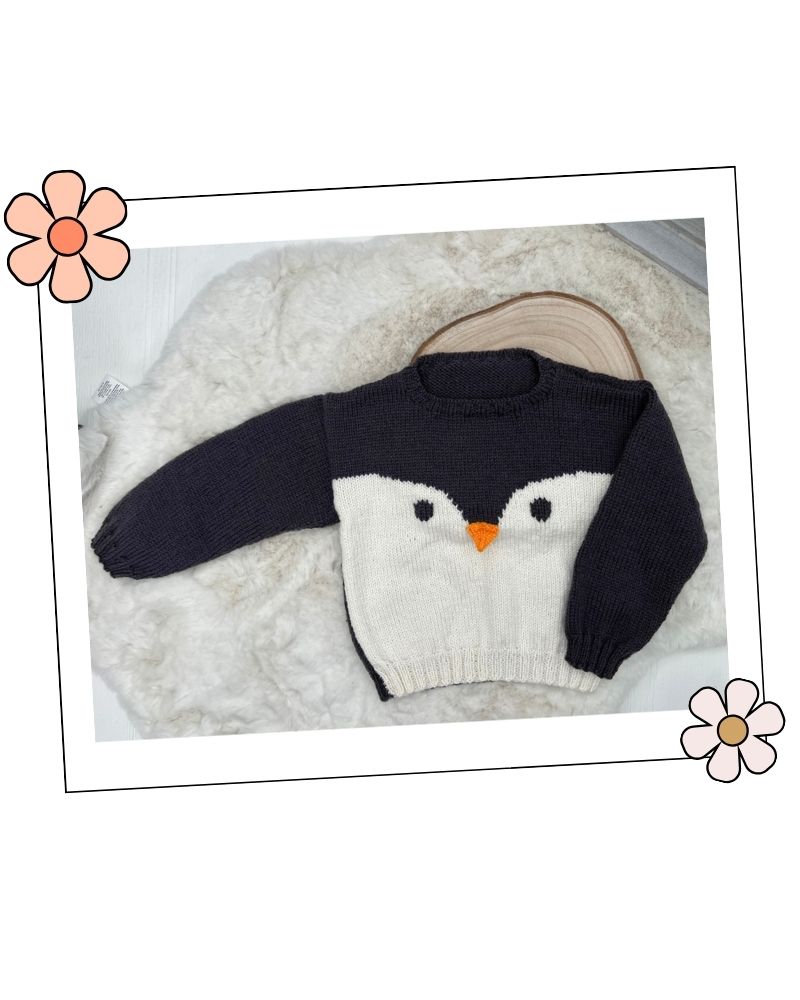 Knitted penguin hat laid flat with ear flaps and white face band, DK hat knitting pattern