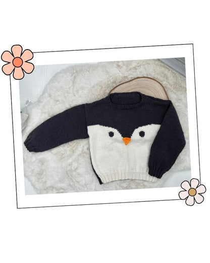 Knitted penguin hat laid flat with ear flaps and white face band, DK hat knitting pattern