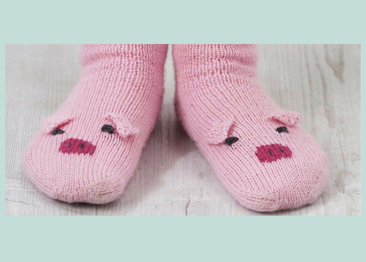 Front view of kids pig socks in pink 4ply yarn, each toe with a Swiss darned snout and embroidered eyes