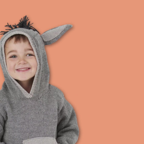 grey knitted hooded sweater with light grey kangaroo style pocket on the front, large donkey ears and a black mane create this cute donkey hoodie knitting pattern by jane burns