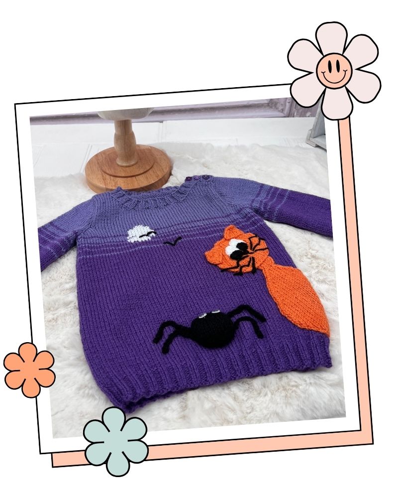 Scaredy Cat jumper laid flat on a white rug, purple children's jumper knitting pattern with cat and spider
