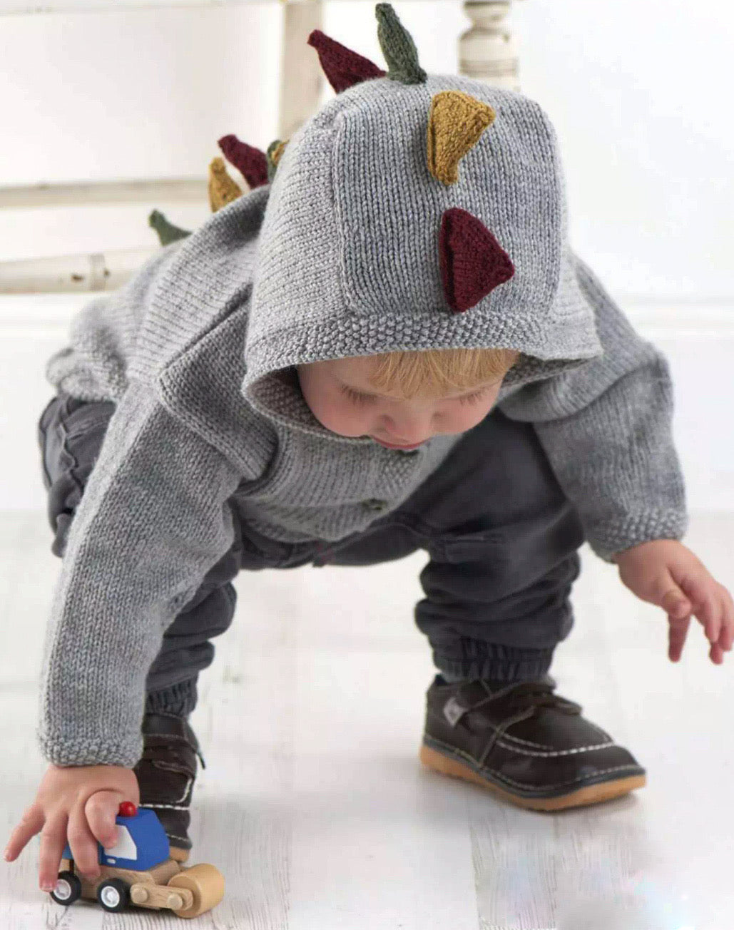 dinosaur hooded cardigan dino hoodie baby knitting pattern with spikes and tail, jane burns. Simple hooded cardigan with spikes and tail to bring the dinosaur roaring to life.