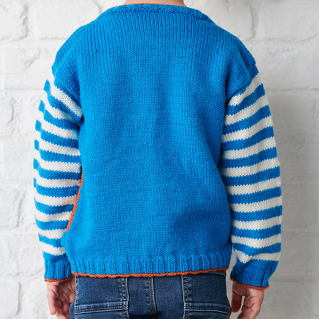 Monstrous kids sweater knitting pattern, a blue sweater with striped sleeves. A large red section across the tummy with knitted teeth and large googly eyes makes this jumper both cute and terrifying, no intarsia. Knitting pattern by Jane Burn